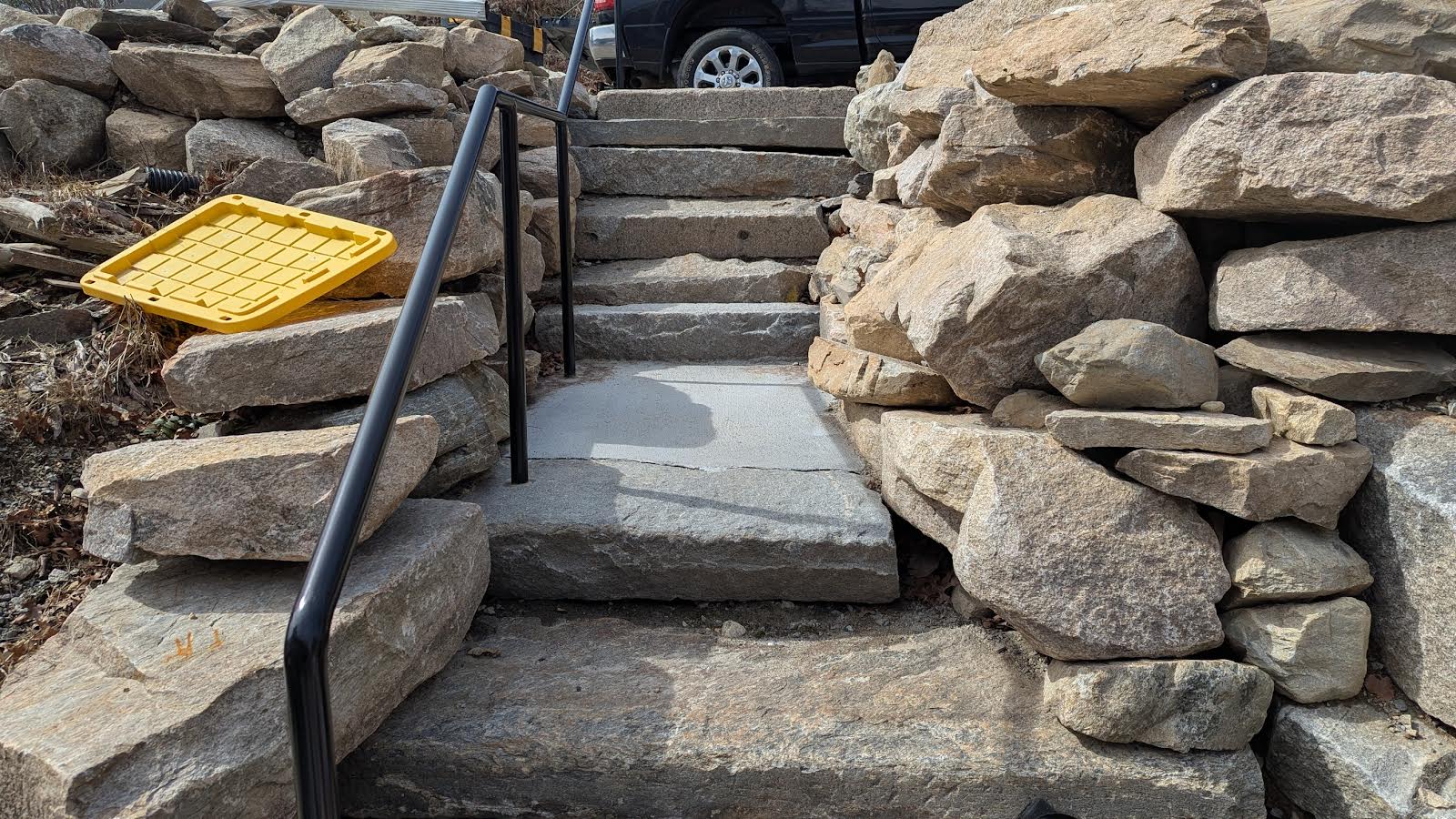 Custom stone steps with metal railing and boulder retaining walls