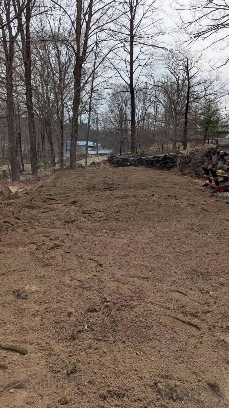 Graded residential yard with stone retaining wall and trees