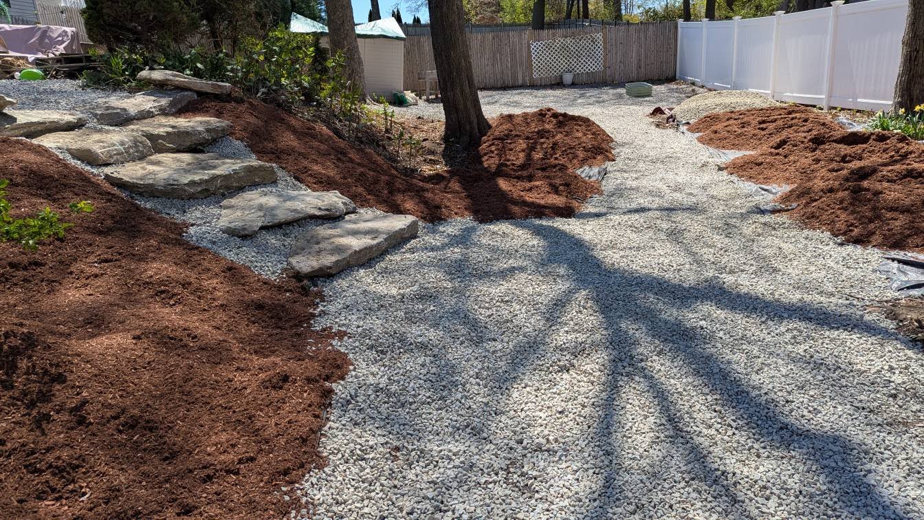 Completed landscaping with gravel pathways, mulch beds, and large stone steps