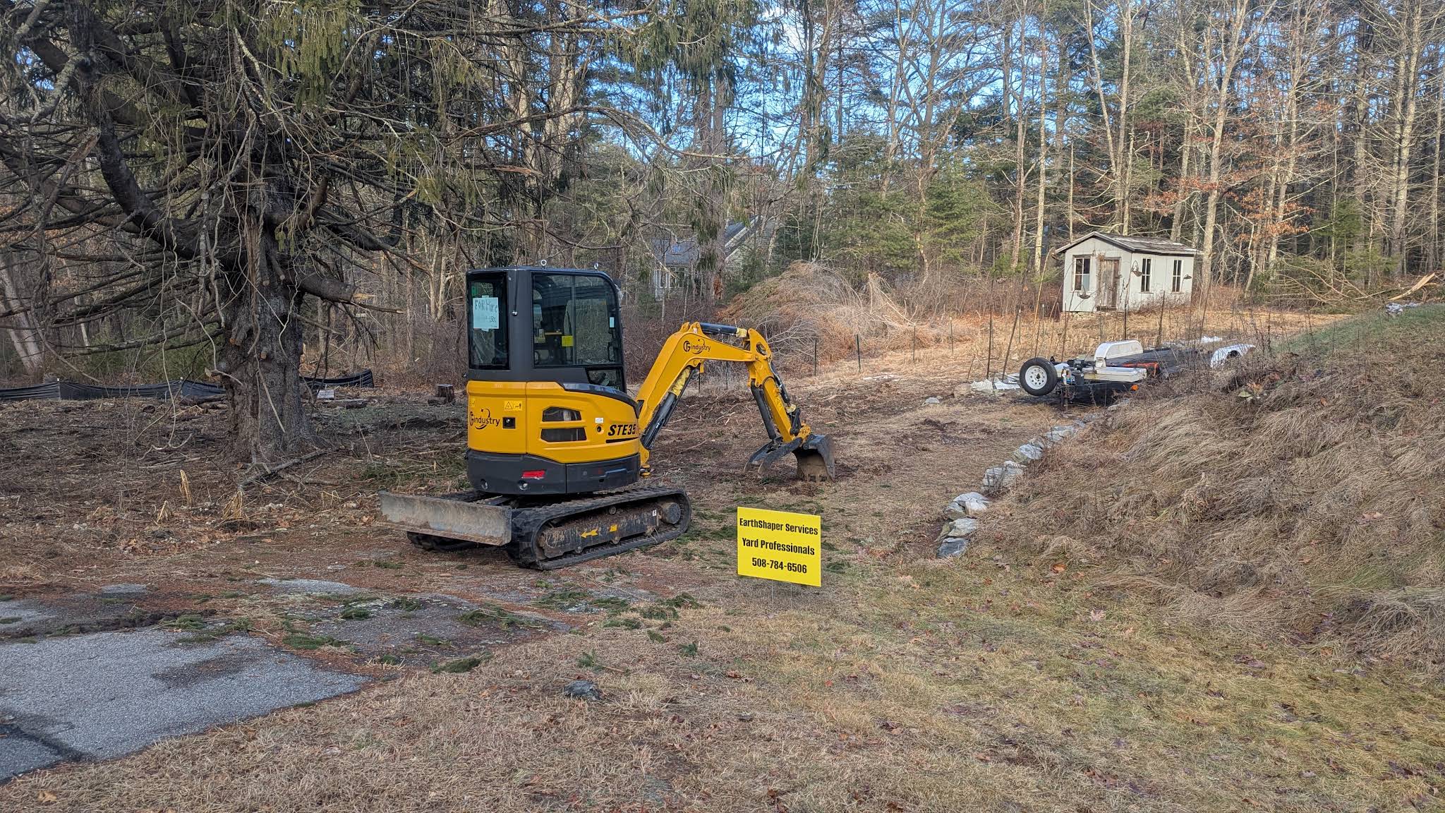 Yellow excavator with EarthShaper Services signage